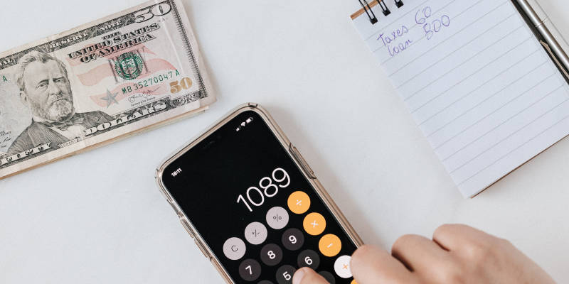 Anonymous Person Calculating Profit on Smartphone Calculator Near Banknotes and Money, Estate Planning Attorney.