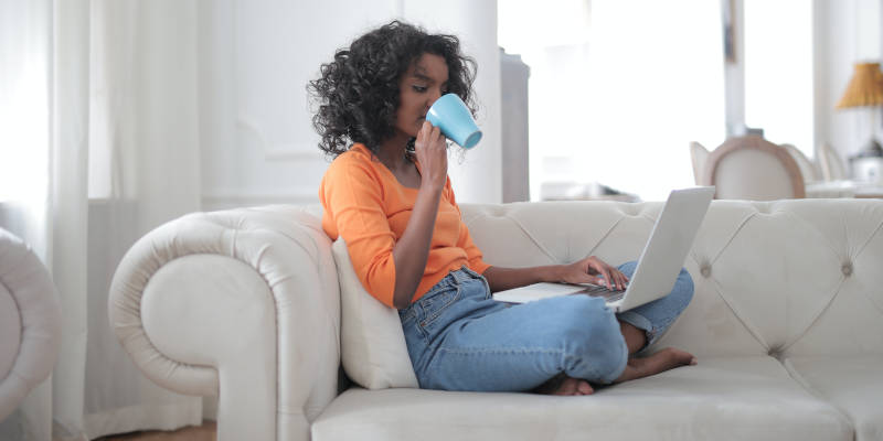 A Woman Sitting on a White Sofa Doing Her Executor's Duties While Drinking Coffee, Corona Estate Planning Attorney.