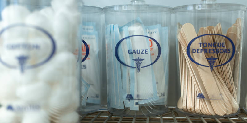 Cotton Balls, Cotton Swabs, and Tongue Depressors in Canisters on a Metal Shelving at Doctor's Office with Corona Estate Planning Attorney