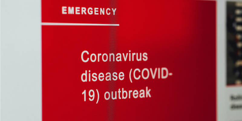 A sign that said "Emergency - Coronavirus disease (covid-19) outbreak on a red background - Pandemic May Affect Long-Term Care Insurance