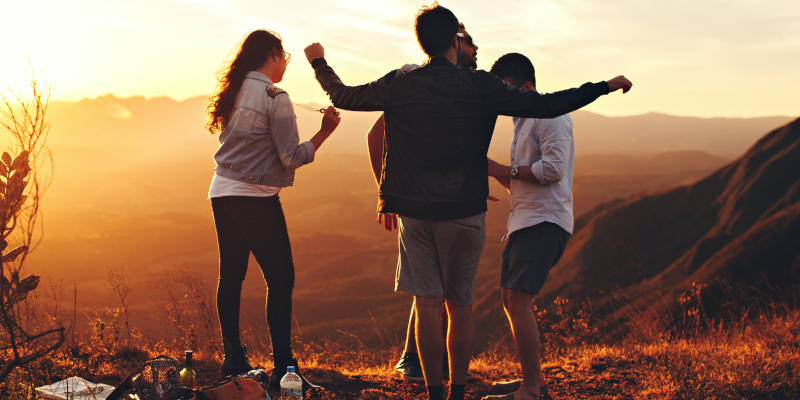 Four Young Individuals Dancing on Top of a Hill, Watching the Sun Set: A Beautiful Moment Captured with Estate Planning Attorney and Estate Plan Modifications in Mind